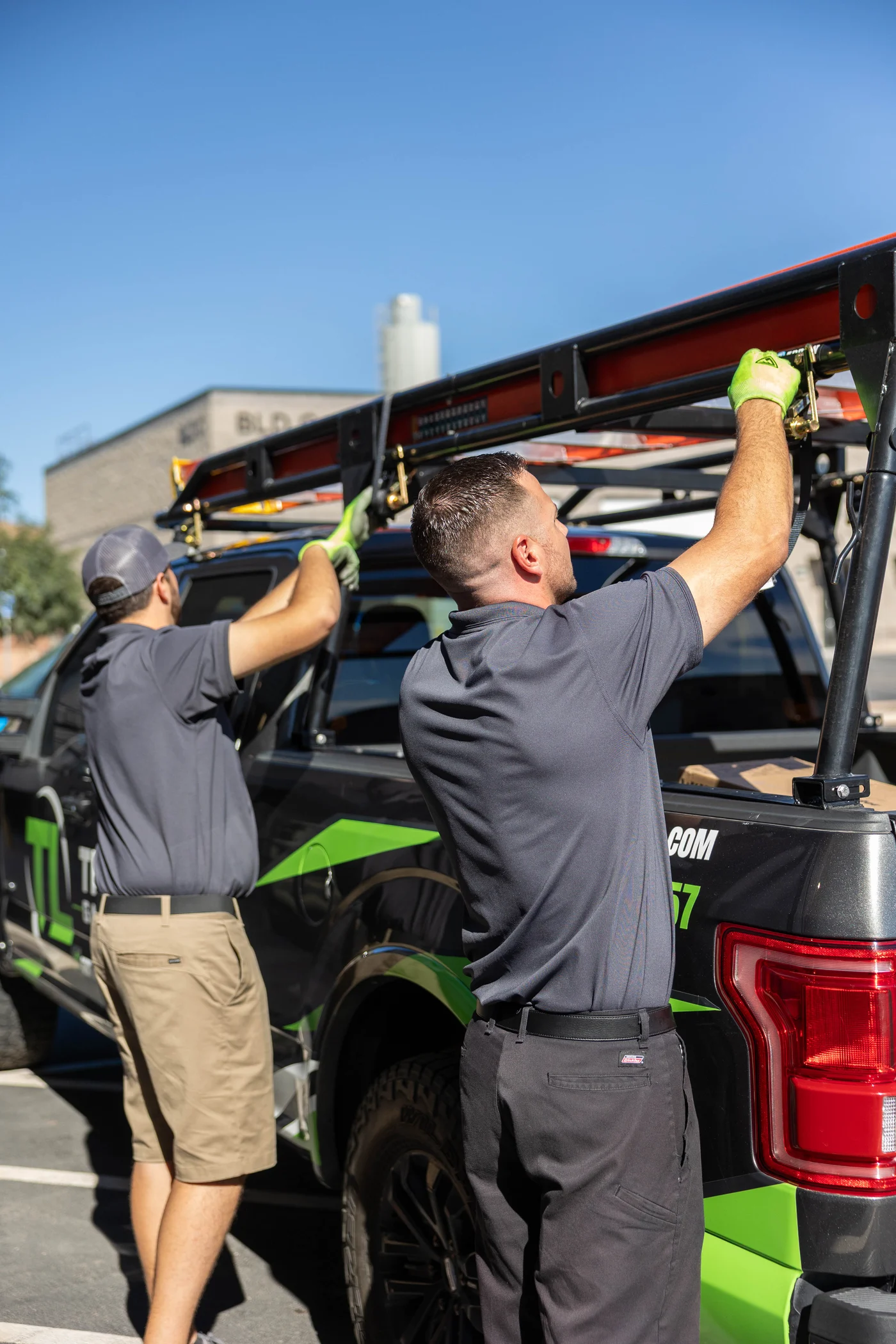 Two True Lift team members securing a ladder to their service truck.